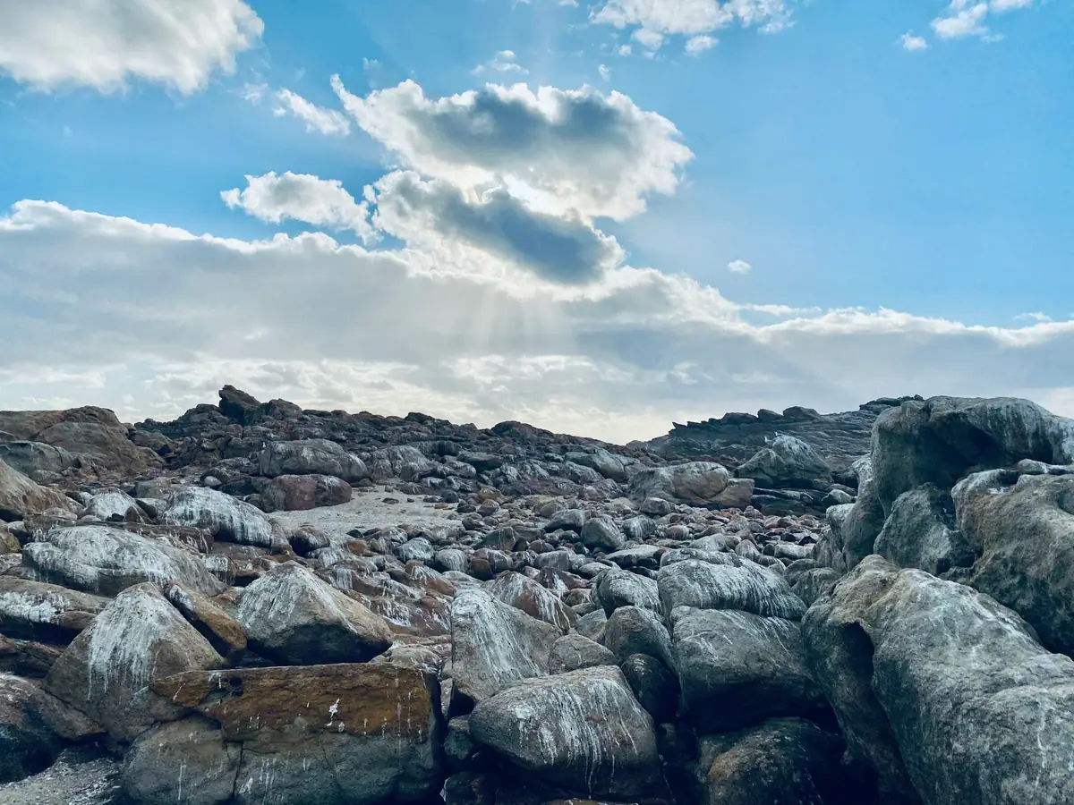 Weathered granite boulders at Moses Rocks under a bright sky with sunbeams breaking through clouds